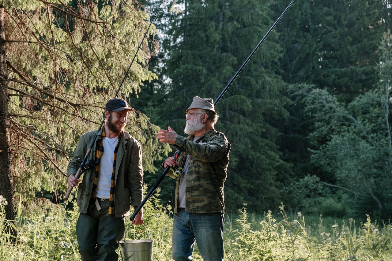 A joyful scene of two men fishing together in a lush forest area, sharing a moment outdoors.